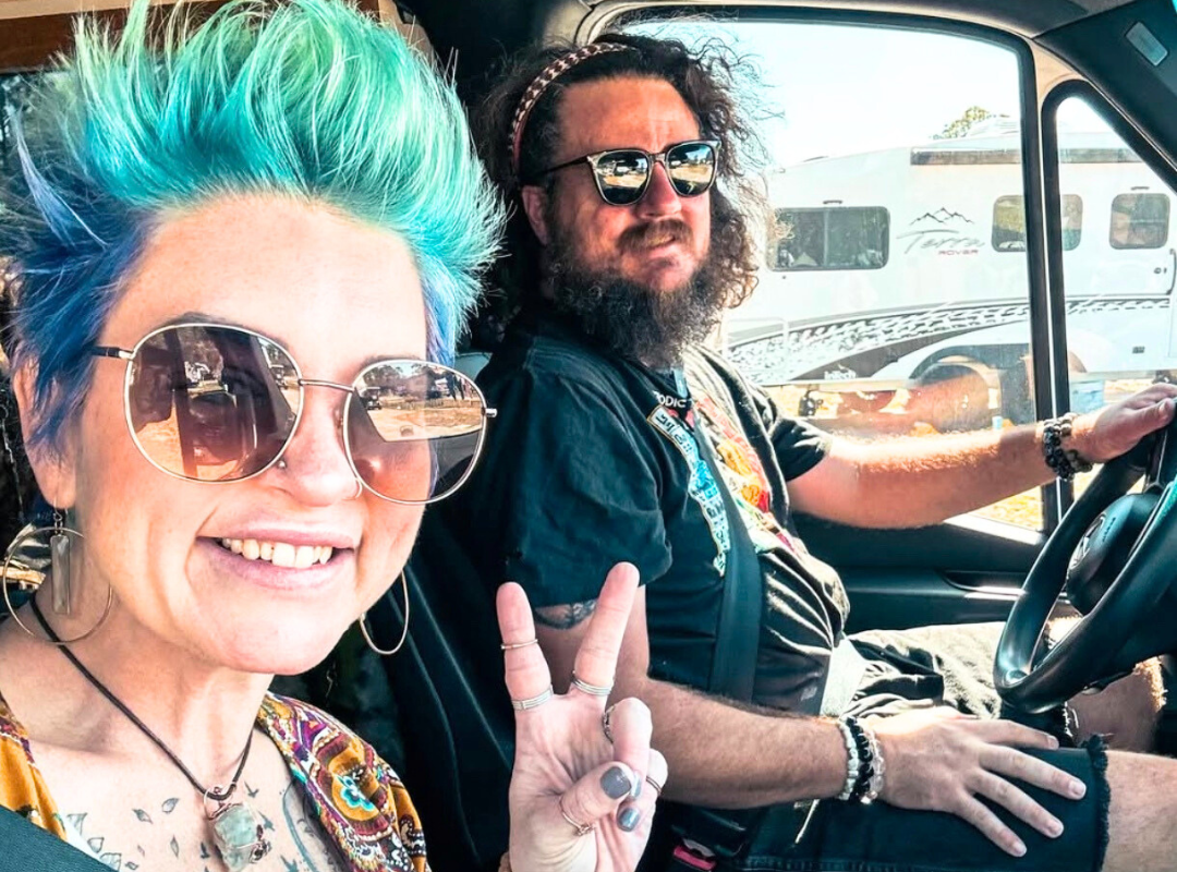 Jenn and Kyle Bethune in their van with a peace sign in happiness