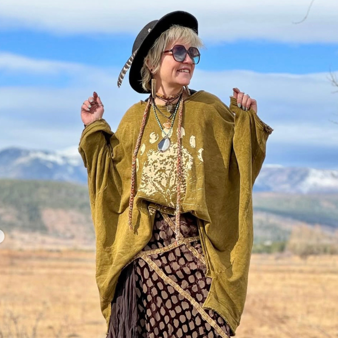 Jenn in a flowing gold blouse with a mountain backdrop